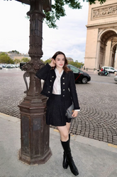 a lady wears a ruffle neck top with black tweed jacket and a black mini skirt